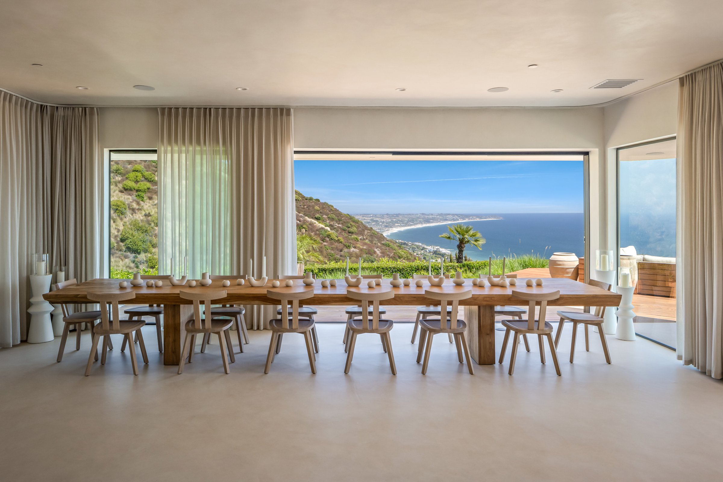 A long dining table before a wall of glass and the ocean